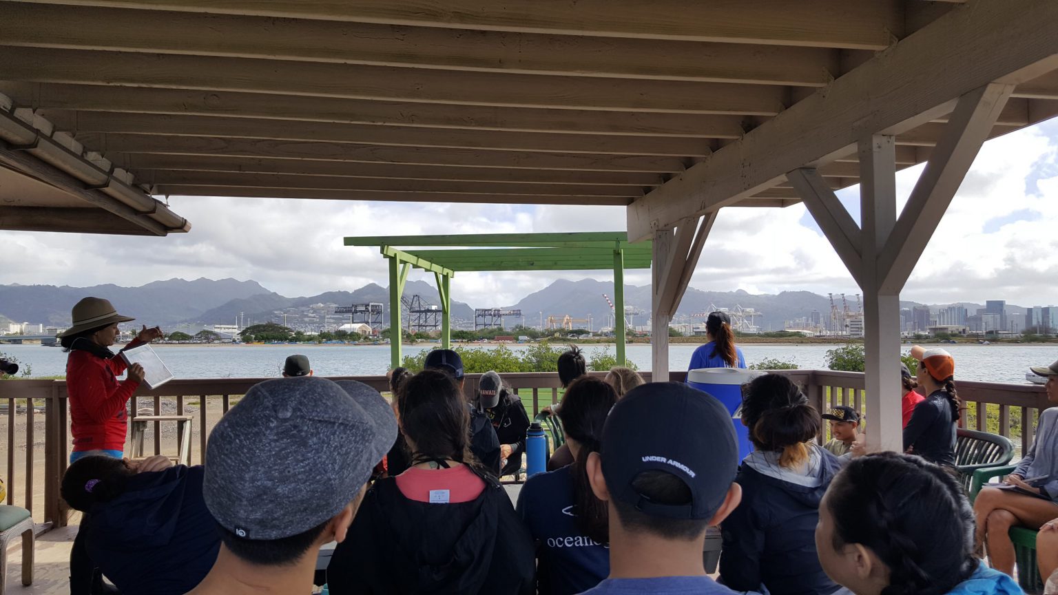 Students listening to presentation about Mokauea on one of the house decks on Mokauea.